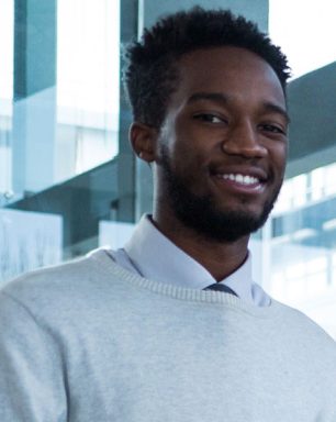 a man in a sweater and tie standing next to another man.