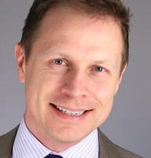 a man in a suit and tie smiling at the camera.